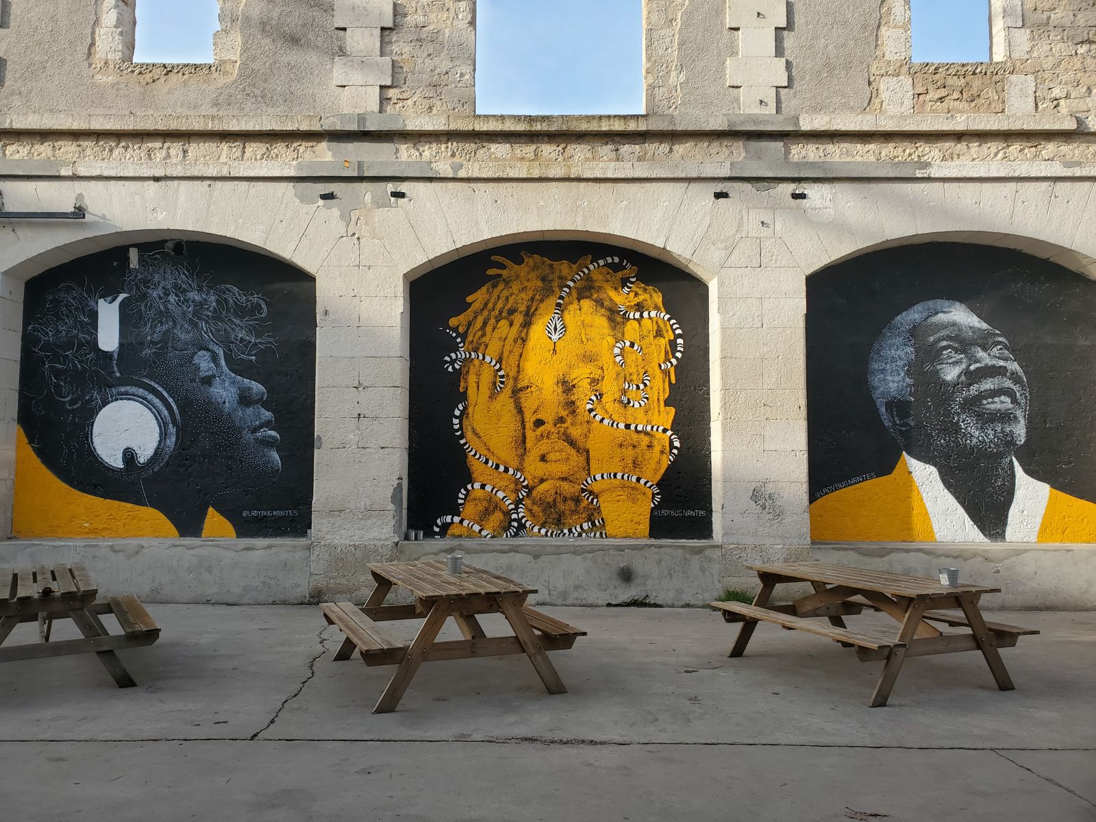 Murales de arte urbano con rostros pintados sobre una pared de piedra