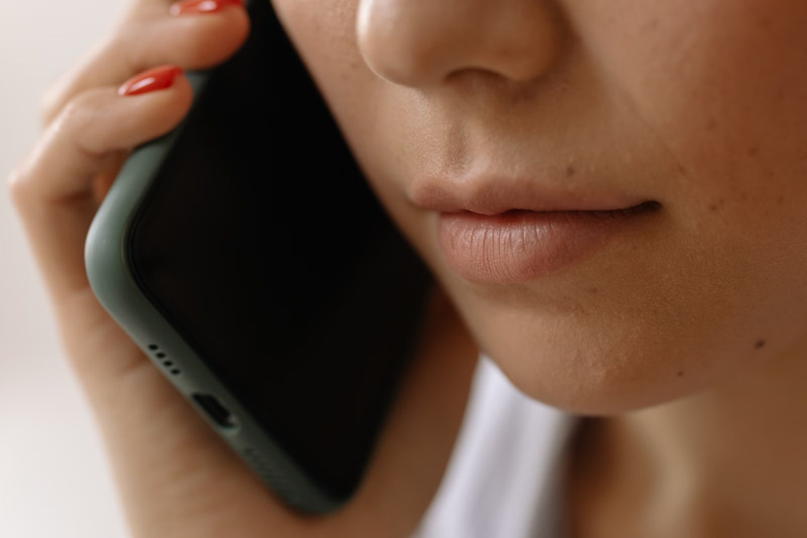 Primer plano de una mujer atendiendo una llamada con el celular en la oreja