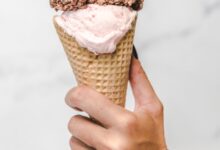 Mano sosteniendo un cucurucho de helado con dos gustos
