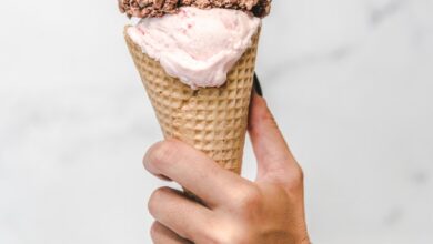 Mano sosteniendo un cucurucho de helado con dos gustos