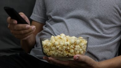 Persona con un bowl de pochoclos y el control remoto en una noche de películas