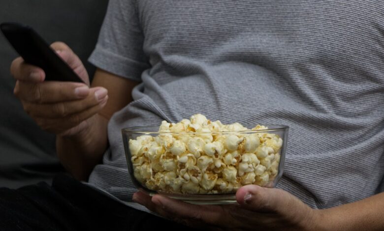 Persona con un bowl de pochoclos y el control remoto en una noche de películas
