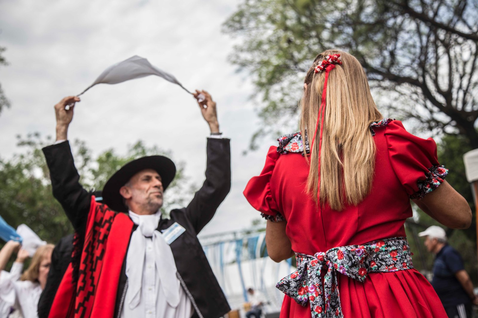 Pareja de bailarines de folclore con pañuelos, ella con vestido rojo y él con sombrero