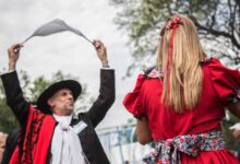 Pareja con trajes tradicionales bailando una zamba con pañuelo al aire libre en Rosario