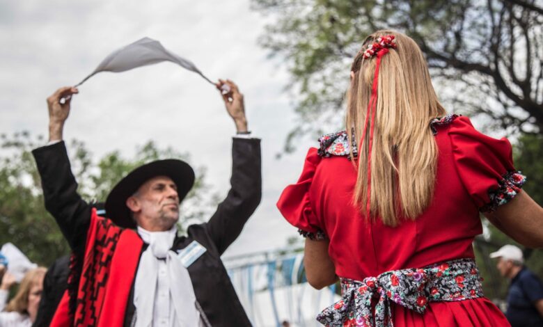 Pareja con trajes tradicionales bailando una zamba con pañuelo al aire libre en Rosario