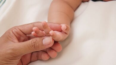 Mano de una persona adulta sosteniendo la mano de un bebé recién nacido