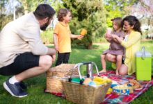Familia haciendo un picnic sobre el pasto en un parque soleado
