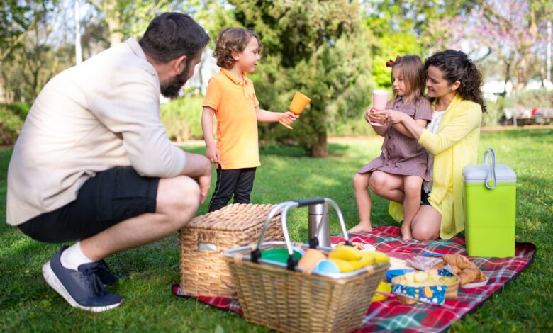 Familia haciendo un picnic sobre el pasto en un parque soleado