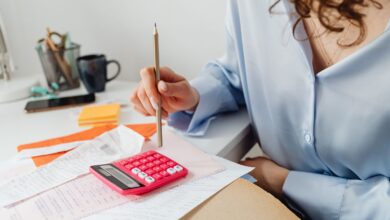 Mujer calcula gastos con una calculadora y papeles sobre el escritorio