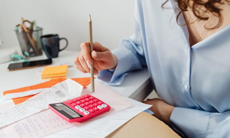 Mujer calcula gastos con una calculadora y papeles sobre el escritorio
