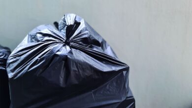 Bolsa de residuos negra cerrada apoyada contra una pared