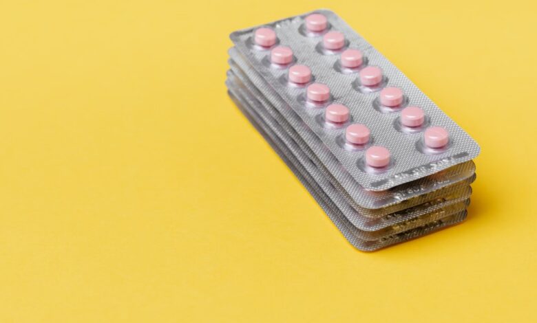 Blísters de pastillas apilados sobre un fondo amarillo