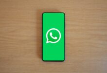 Celular con el logo de WhatsApp en la pantalla sobre una mesa de madera