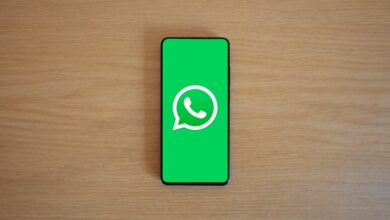 Celular con el logo de WhatsApp en la pantalla sobre una mesa de madera
