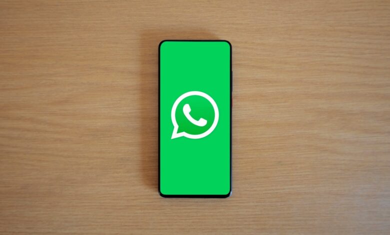 Celular con el logo de WhatsApp en la pantalla sobre una mesa de madera