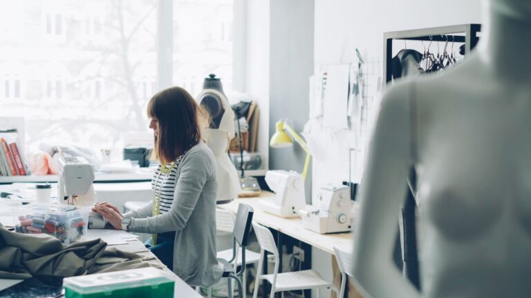 Emprendedora cose en una máquina en su taller de diseño de indumentaria