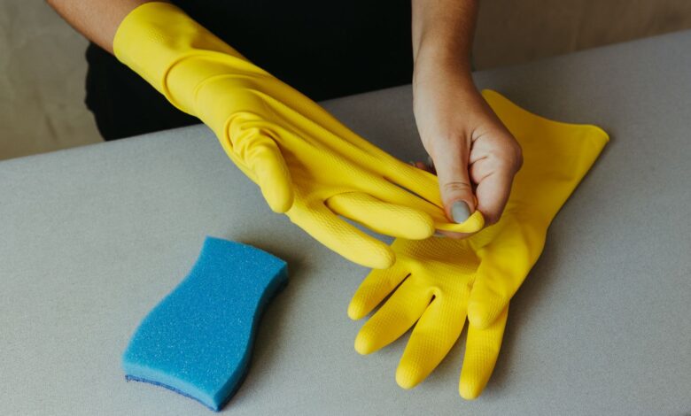 Guantes de goma amarillos y esponja para tareas de limpieza en una casa