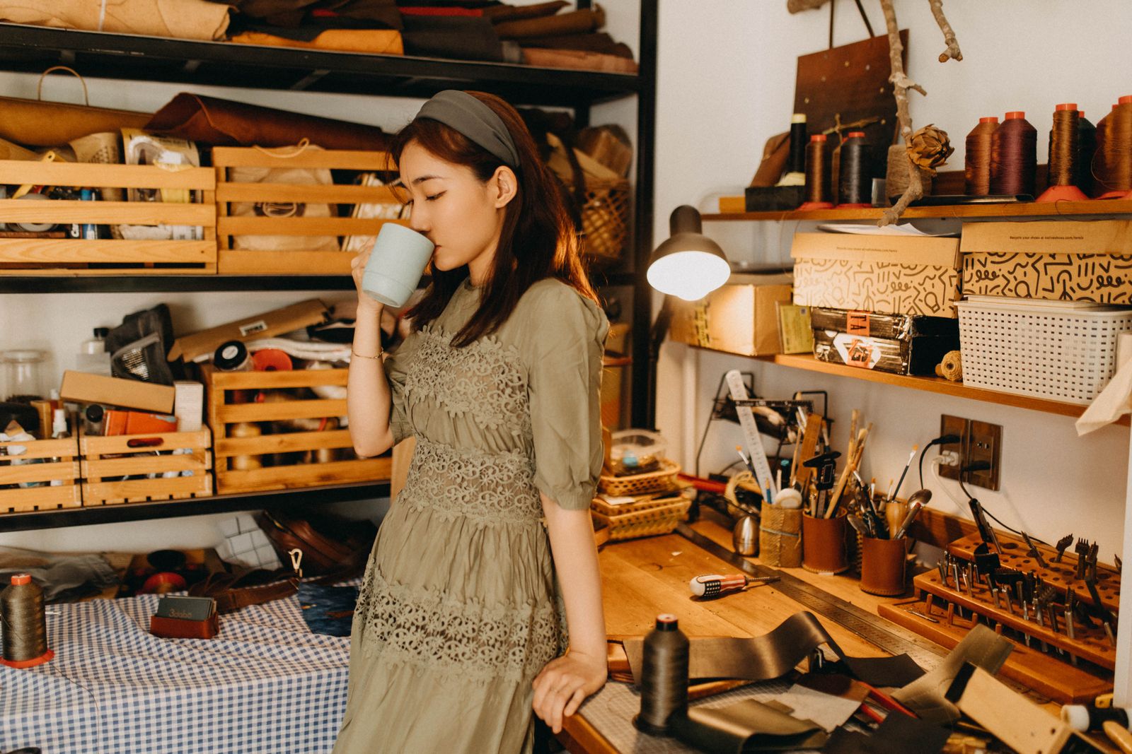 Emprendedora toma un café en su taller de manualidades rodeada de herramientas y materiales
