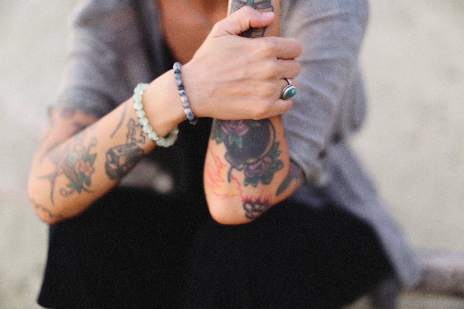 Brazos de mujer con tatuajes pequeños, pulseras y anillos