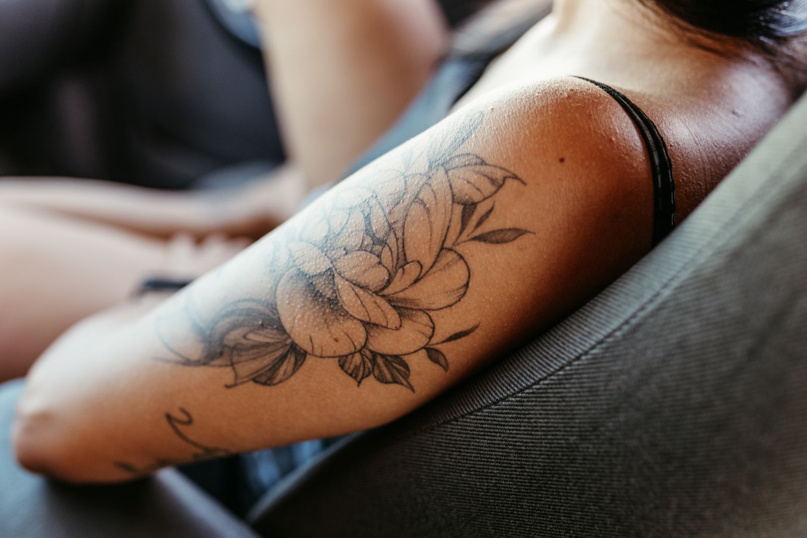 Brazo de una mujer con un tatuaje floral detallado de líneas finas