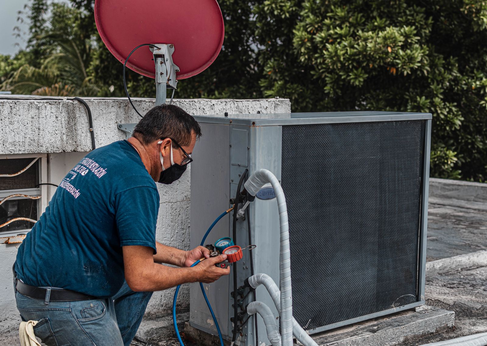 Técnico revisando una unidad exterior de aire acondicionado con un manómetro