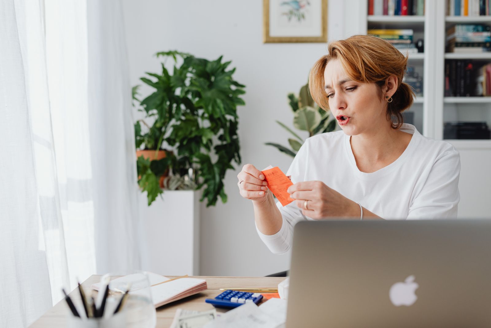 Mujer revisa facturas en su casa con una laptop para hacer un trámite online