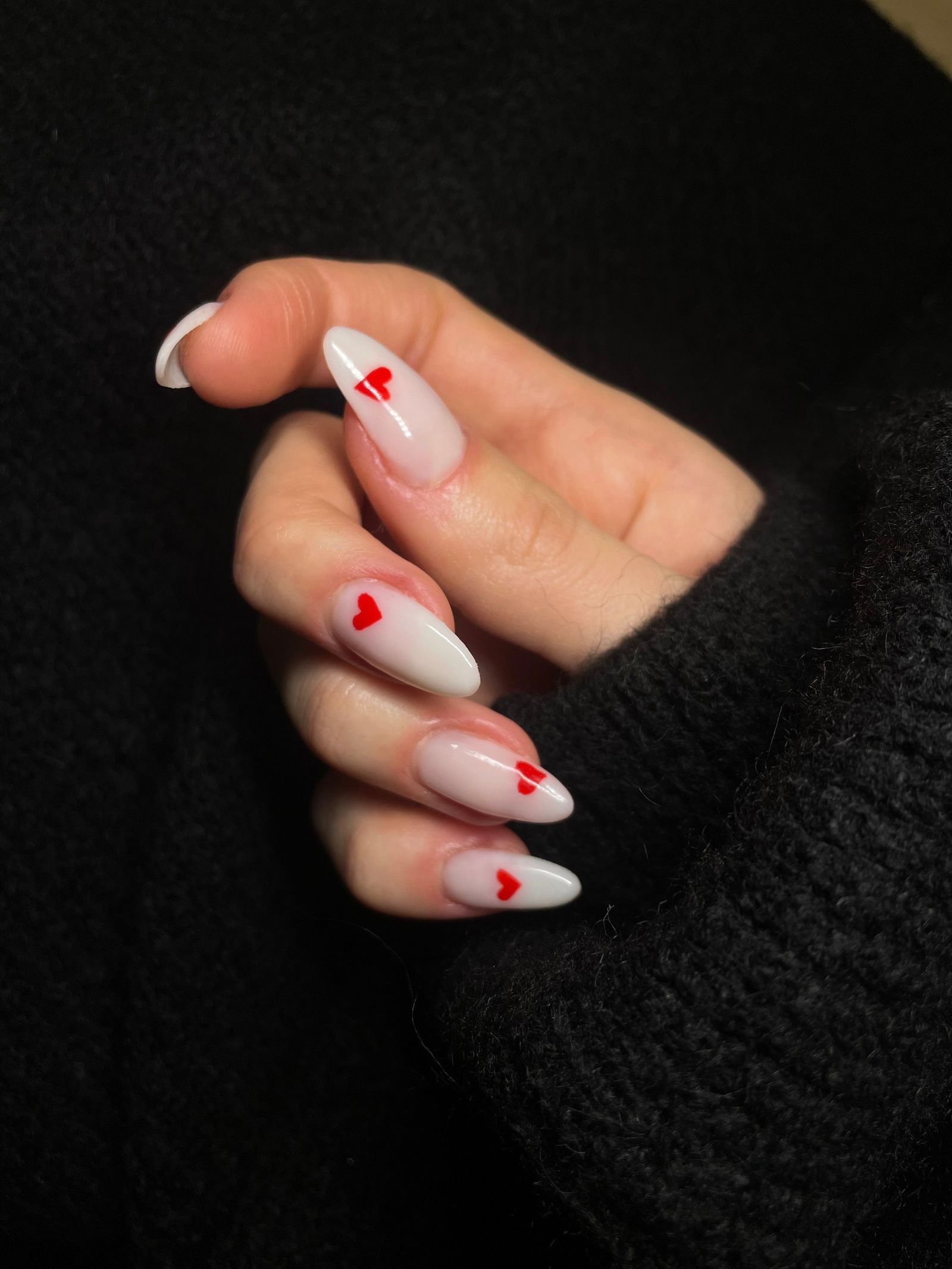 Uñas nude con pequeños corazones rojos pintados a mano