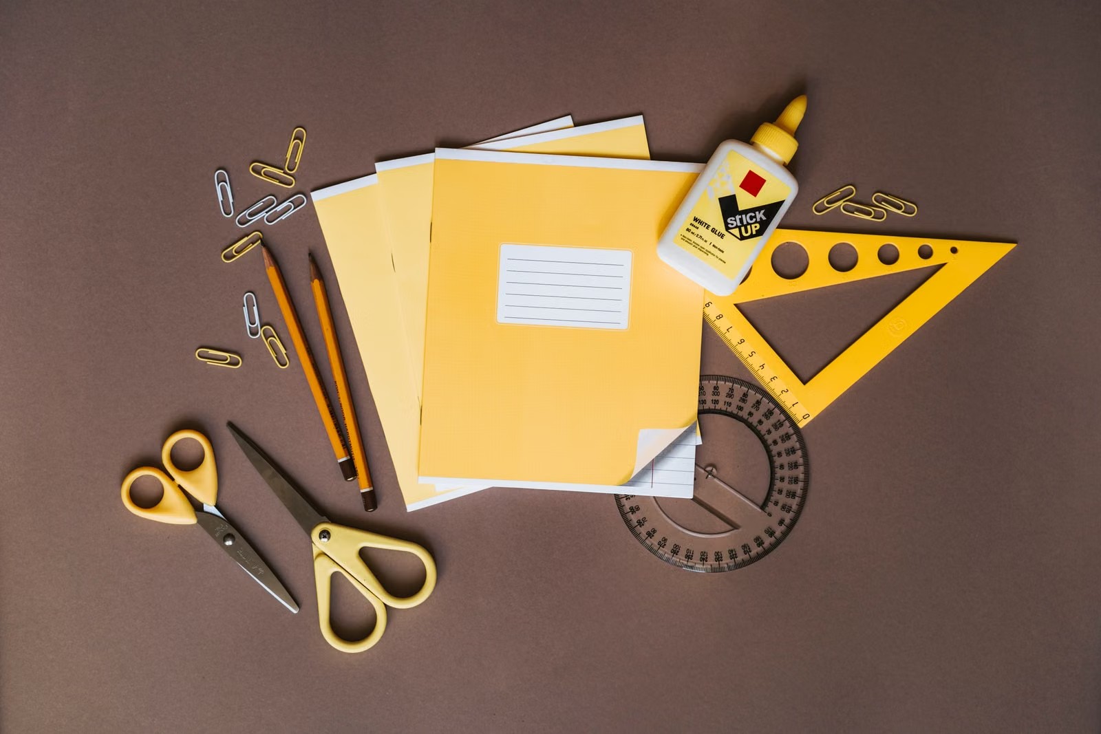Cuadernos, lápices, tijera y escuadra sobre una mesa