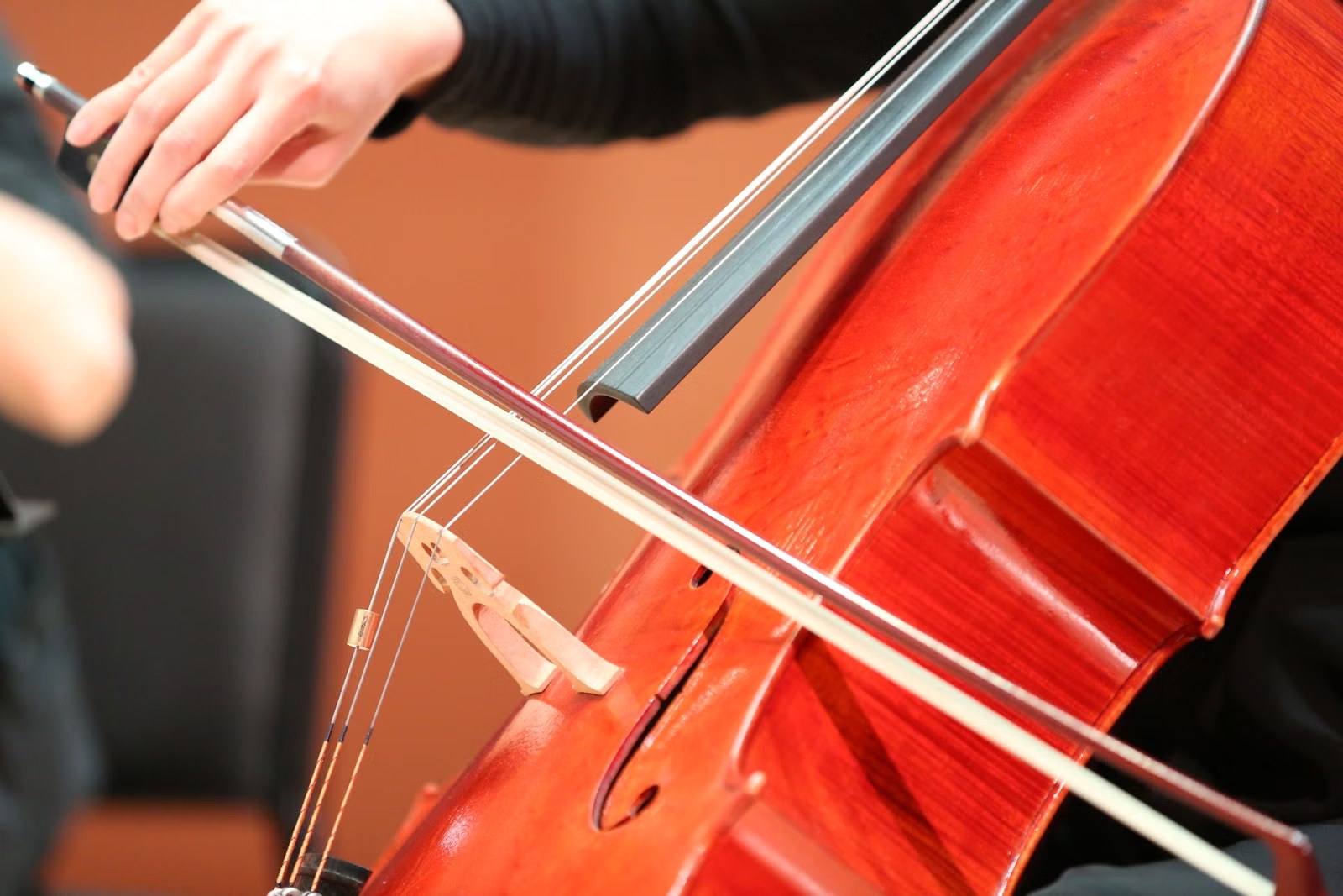 Manos tocando un violonchelo con arco en un concierto