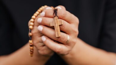 Manos que sostienen un rosario de madera con una cruz