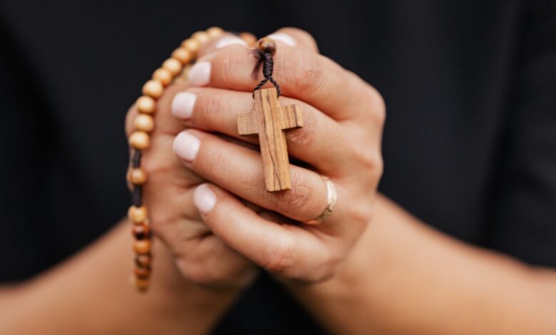 Manos que sostienen un rosario de madera con una cruz