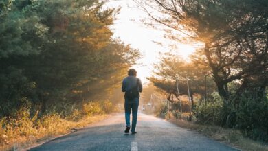 Hombre caminando por un sendero arbolado con luz de amanecer