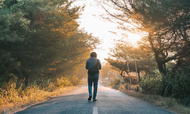 Hombre caminando por un sendero arbolado con luz de amanecer